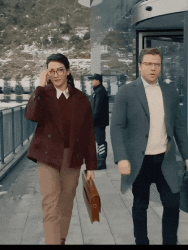 a man and a woman are walking down a sidewalk with a briefcase