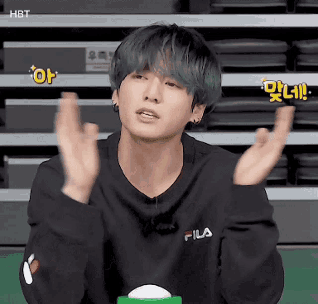 a young man with green hair is wearing a black fila sweater