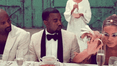a man in a tuxedo sits at a table with glasses of water