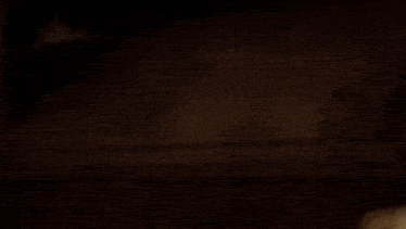 a close up of a woman 's face in a dark room with a light behind her .