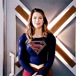 a woman is wearing a superman costume and standing in front of a door .