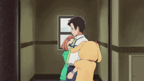 a man and woman are hugging in a hallway