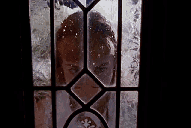 a woman looks through a stained glass door
