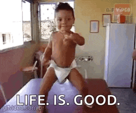 a baby in a diaper is standing on a table with the words `` life is good '' .
