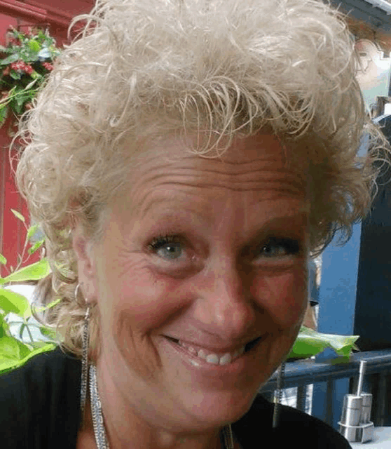 a close up of a woman 's face with curly blonde hair smiling .