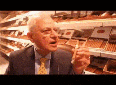 an older man in a suit and tie smoking a cigar