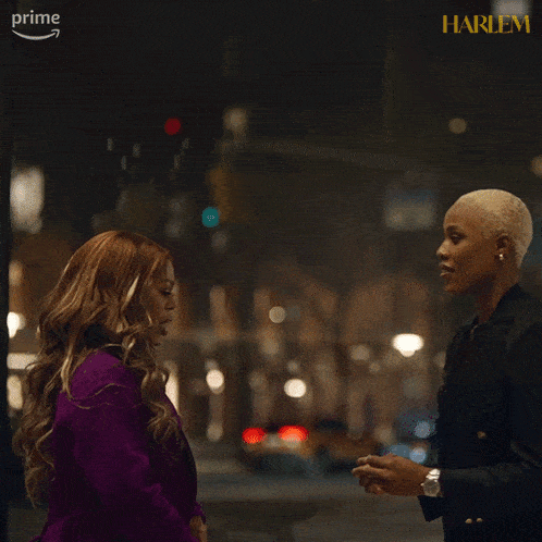 two women are standing next to each other in front of a sign that says harlem on it