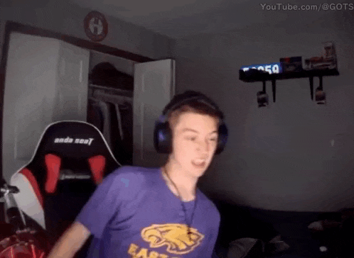 a man wearing headphones and a purple shirt is standing in a dark room .
