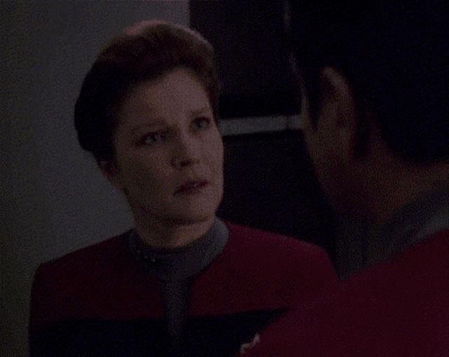 a man and a woman are looking at each other in a dark room .