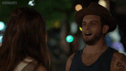 a man wearing a hat is talking on a cell phone with a woman .