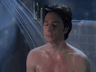 a man is taking a shower with his eyes closed in a bathroom .