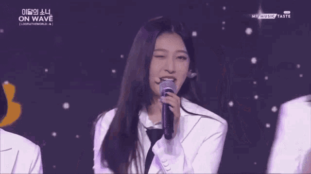 a couple of women standing next to each other on a stage with a microphone .