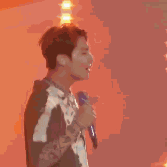 a man in an orange shirt is standing in front of a wall with lights on it .