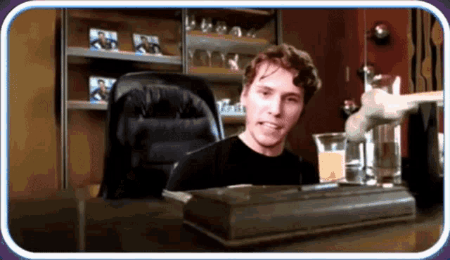 a man sits at a desk with a glass of orange juice