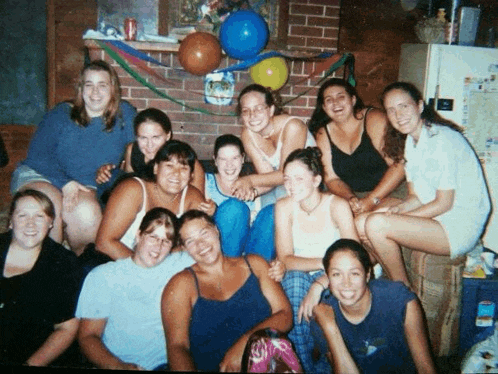 a group of women are posing for a picture in front of a fireplace and balloons