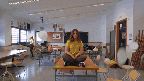 a girl in a yellow shirt sits on a table