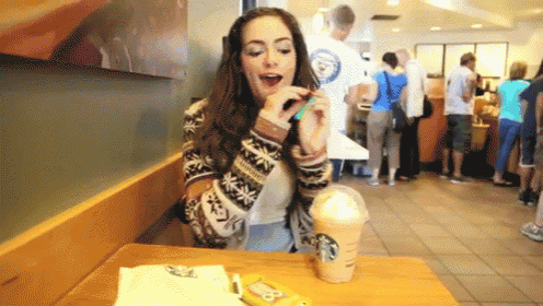 a woman is sitting at a table with a starbucks drink