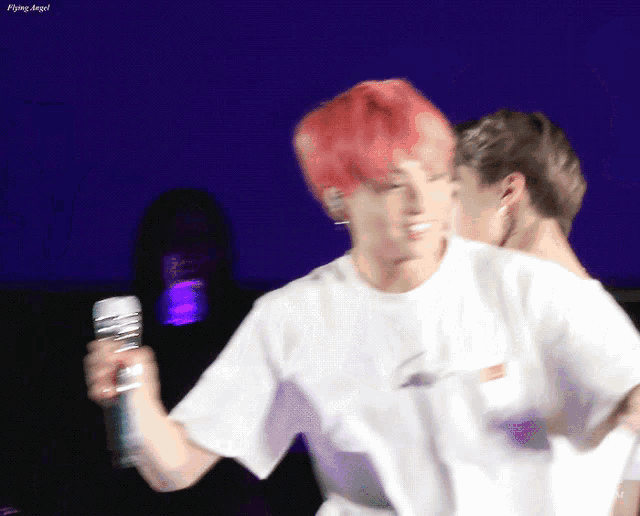 a man with red hair is holding a microphone while another man stands behind him