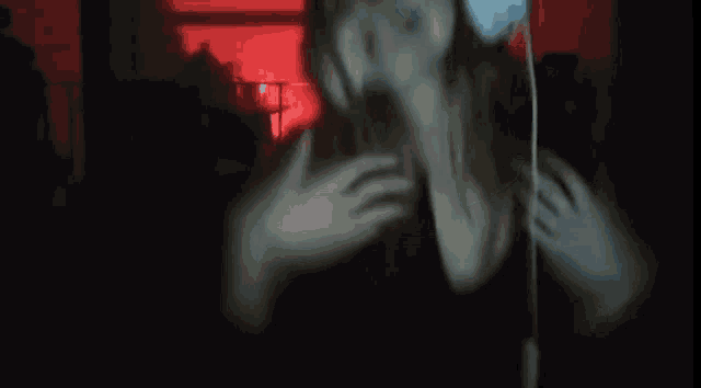 a woman wearing headphones is standing in a dark room .