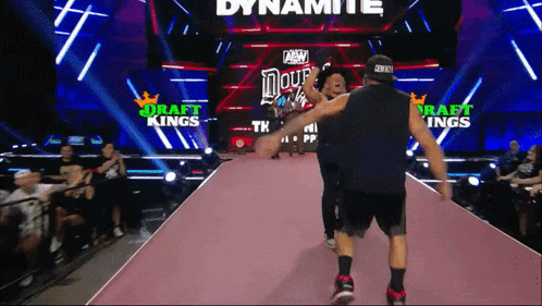 two men are walking down a pink carpet in front of a sign that says dynamite
