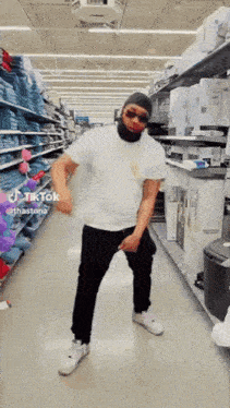 a man is dancing in a store while wearing sunglasses and a hat .