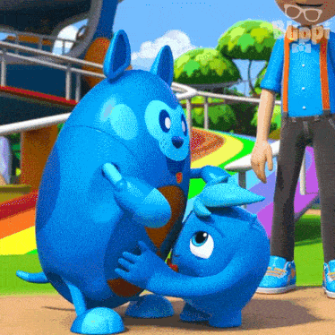 two blue cartoon characters are hugging each other in a park while a boy looks on .