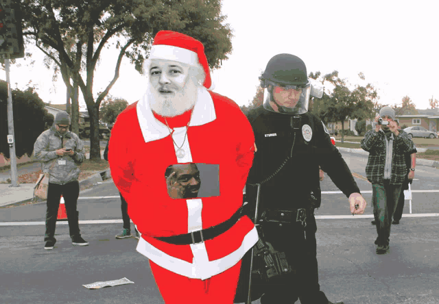 a man in a santa suit is being escorted by a police officer wearing a helmet