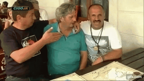 three men are posing for a picture in front of a sign that says cigoja .