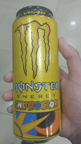 a hand holds a yellow can of monster energy the doctor