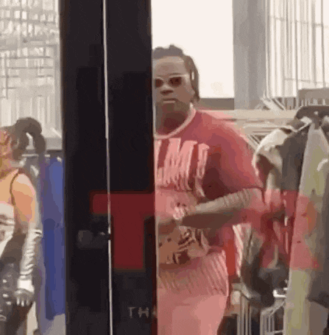 a man in a red shirt is standing in front of a store window .