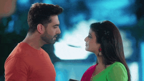 a man and a woman are looking at each other . the woman is wearing a green dress .