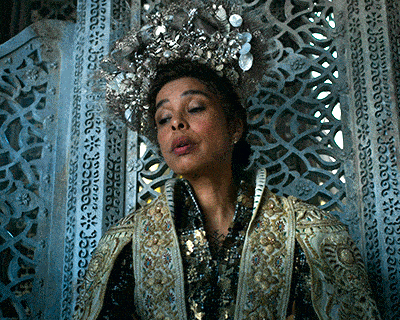 a woman wearing a crown is sitting in front of a wall