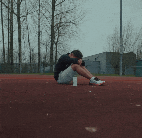 a man sits on the ground with his head down