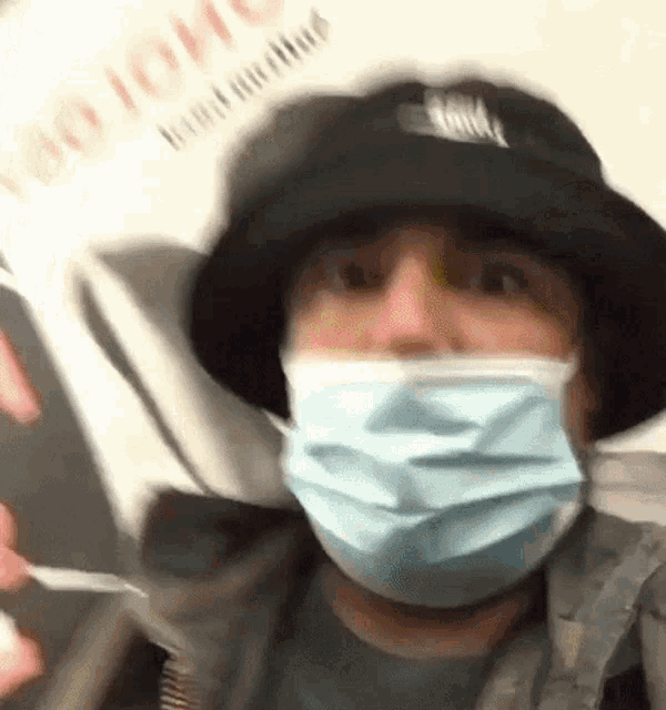 a man wearing a hat and a face mask is riding a train .