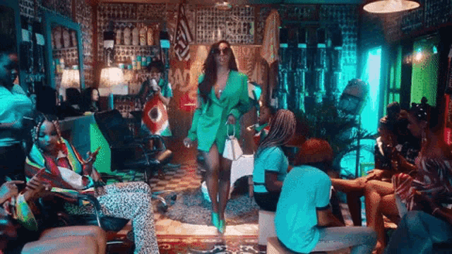 a woman in a green jacket is dancing in a room with people