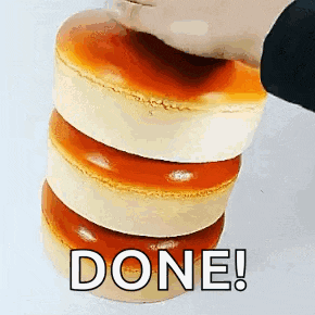 a person is stacking three cakes on top of each other with the word done written on it .