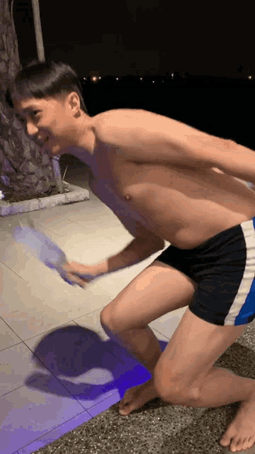 a boy without a shirt is kneeling down on the ground