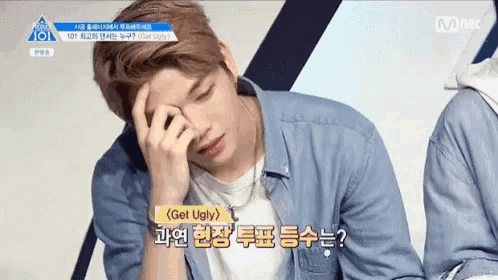 a man in a denim shirt is laying down with his hand on his forehead