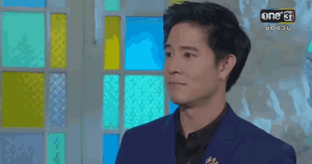 a man in a blue suit is standing in front of a stained glass window with the number 31 on the bottom