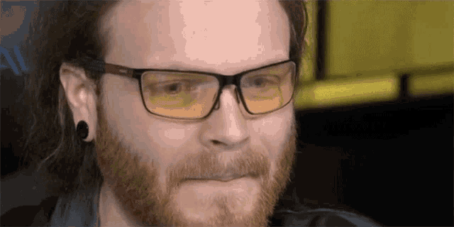 a man with a beard and glasses is making a face .