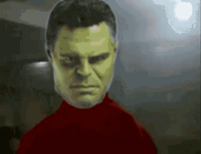 a close up of a man 's face with a green face and a red shirt .