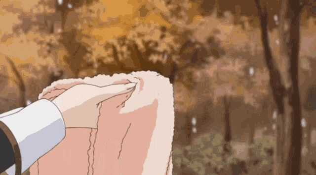 a person is holding a piece of cloth in front of a forest