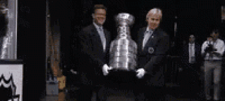 two men are holding a trophy in front of a sign that says ' kings ' on it