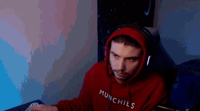a man wearing a red munchies hoodie sits in a chair