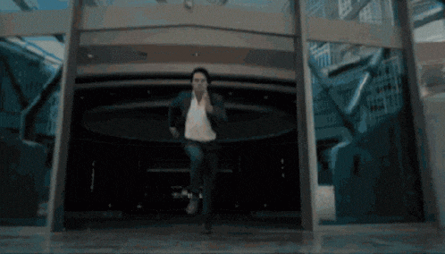 a man in a suit and white shirt is running in a dark room