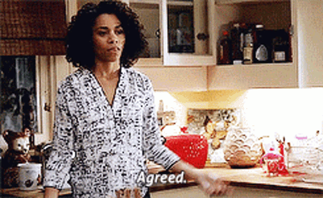 a woman is standing in a kitchen with the word agreed on her shirt
