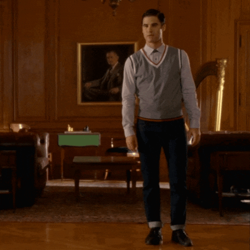 a man standing in a room with a painting of a man on the wall behind him