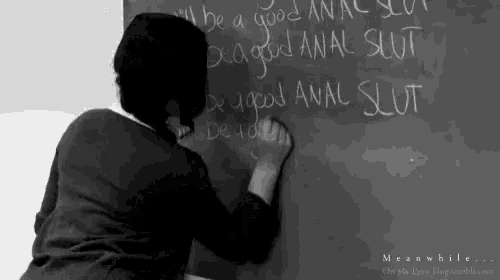a woman is writing on a blackboard with a chalk .
