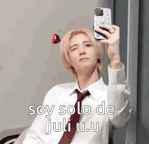 a man in a tie is taking a selfie with his cell phone .