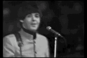 a man is singing into a microphone in a black and white photo .